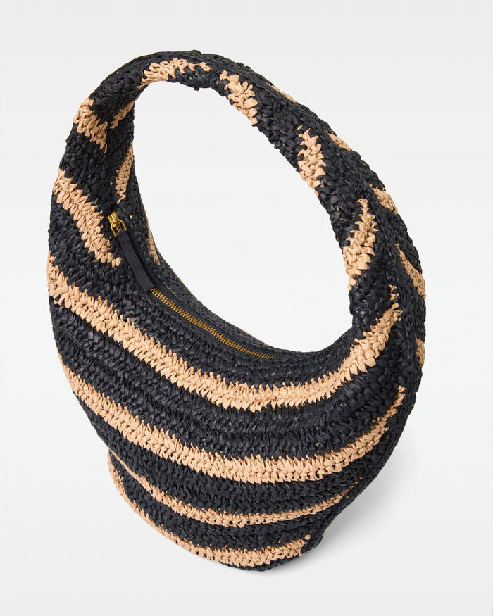 Angled view of the Aya Bag in natural-black showing the woven raffia texture, striped pattern, and gold zipper closure.