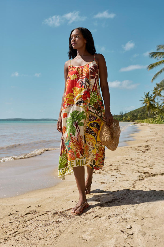 Woman on beach wearing a multicolored tropical scene printed swim cover up