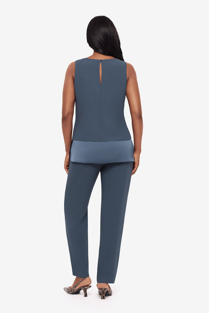 Woman turned away wearing a blue layered tunic blouse with matching jogger pants