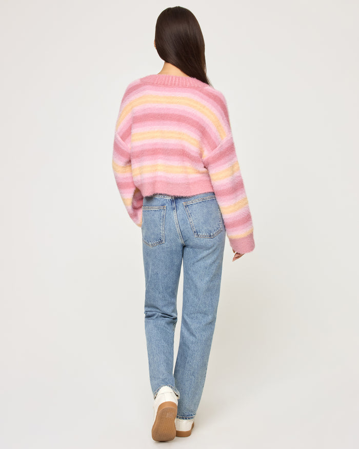 Back view of a model wearing the LSPACE Daybreak Cardigan in daybreak stripe, showing the cropped silhouette and pastel stripe pattern.
