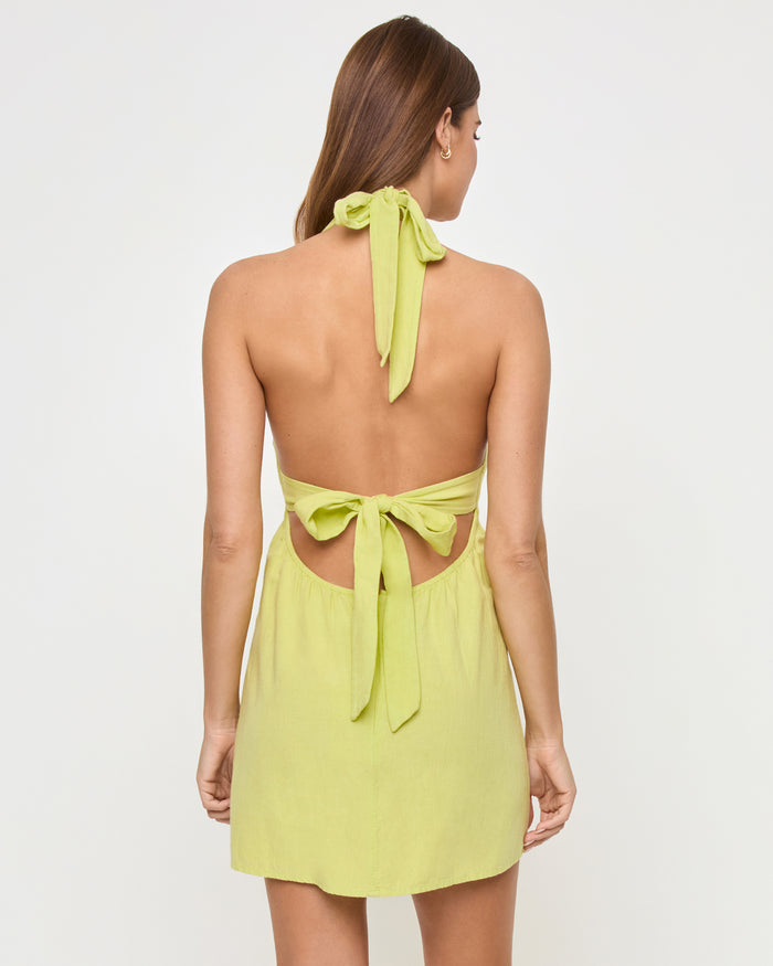 Back view of a model wearing the LSPACE Seabreeze Dress in honeydew, showing the fully open back with bow ties at the neck and waist.