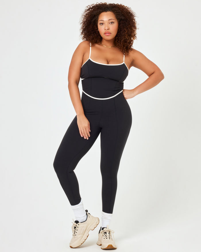 Front view of plus size model wearing the Ace Jumpsuit in black-cream with cream contrast piping.