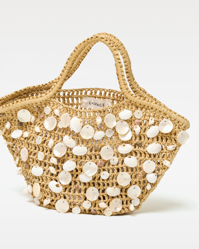Angled view of the cream and natural Alba Bag showing the woven texture and shell detail.