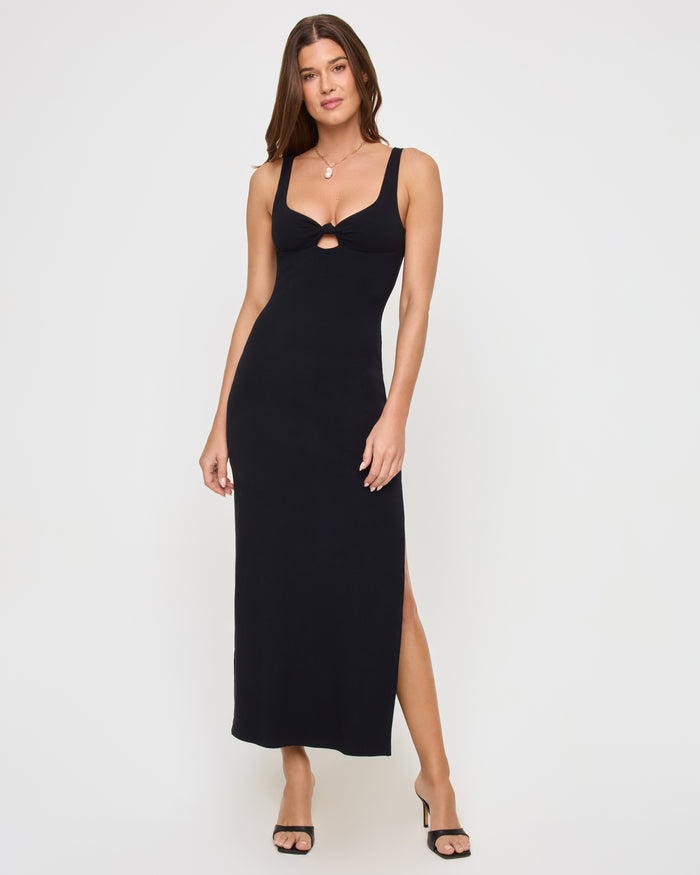Full-length front view of a model wearing the LSPACE Alexis Dress in black, a ribbed maxi dress with a sweetheart neckline, center keyhole cutout detail, and side slit hem.