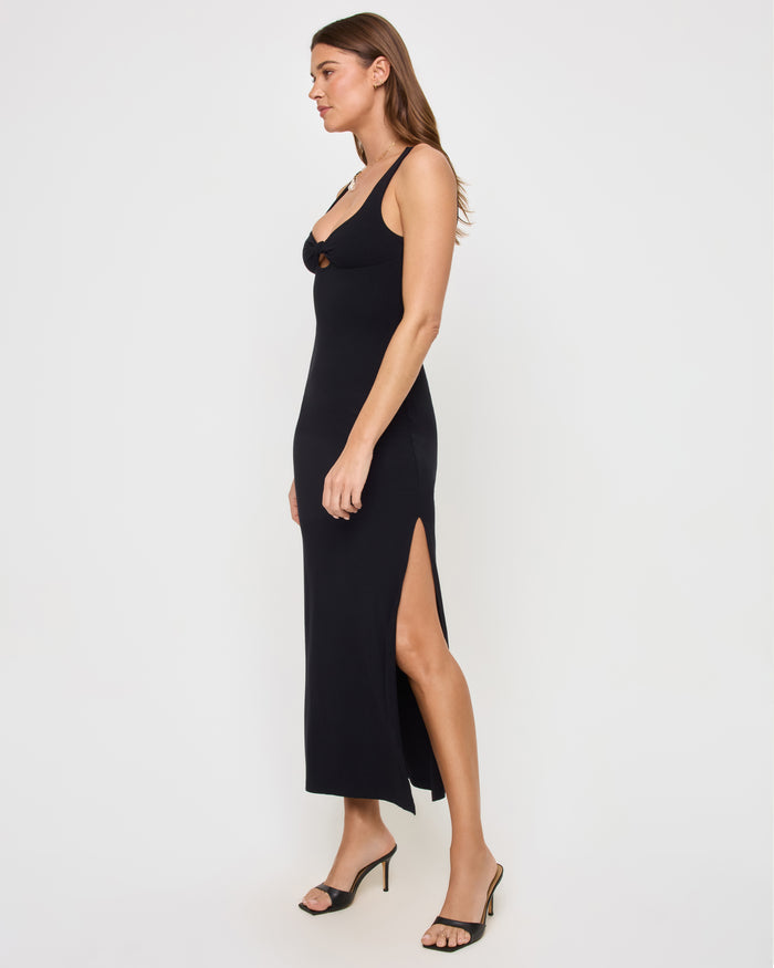 Side view of a model wearing the LSPACE Alexis Dress in black, showing the fitted ribbed silhouette and side slit at the hem.
