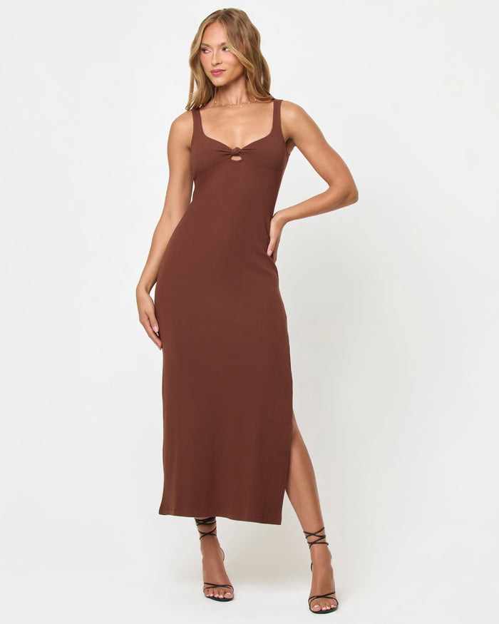 Three-quarter front view of a model wearing the LSPACE Alexis Dress in cafe, a fitted sleeveless midi dress with a sweetheart neckline, front keyhole cutout, and side slit in chocolate brown.