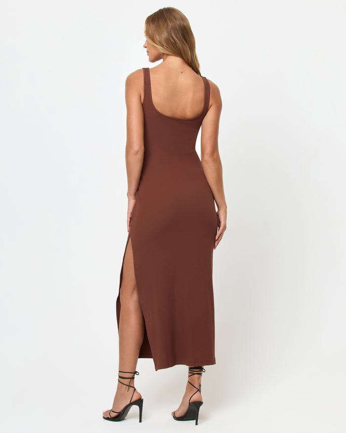 Back view of a model wearing the LSPACE Alexis Dress in cafe, showing the thick straps, open back, and side slit of the fitted ribbed midi dress in chocolate brown.