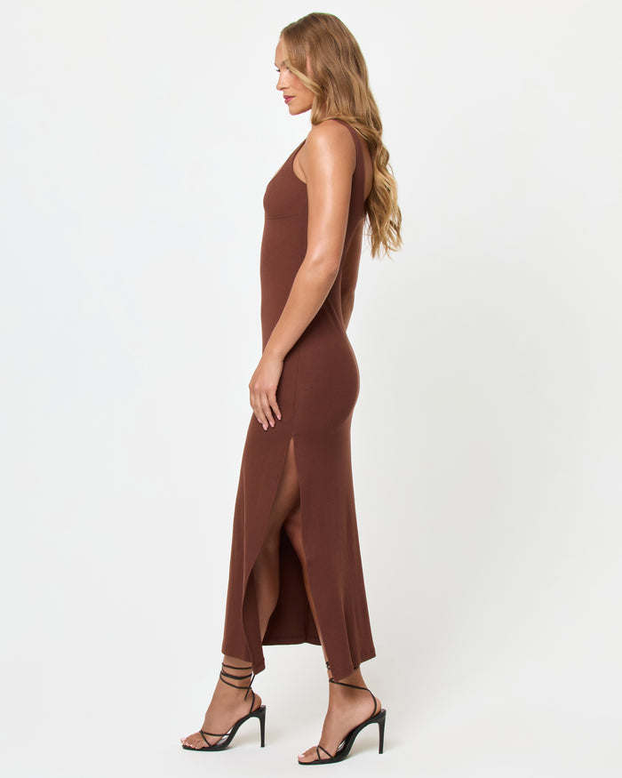 Side view of a model wearing the LSPACE Alexis Dress in cafe, showing the fitted silhouette and side slit of the chocolate brown ribbed midi dress.