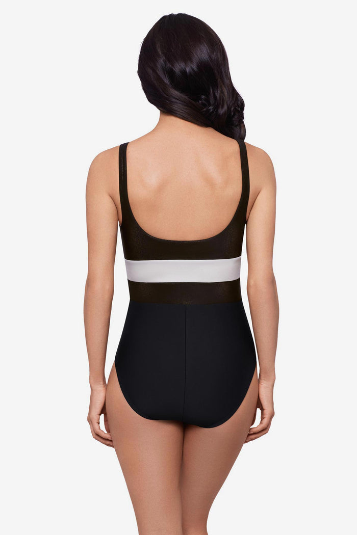 Woman turned away wearing a black one-piece swimsuit with a white stripe in the middle