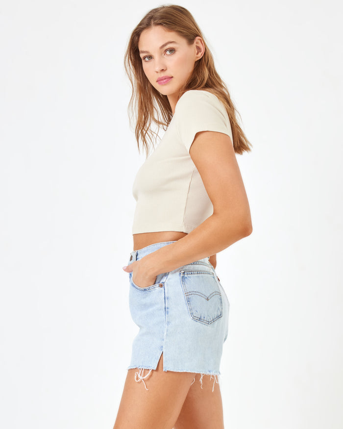 Side view of a model wearing the LSPACE aligrace Michelle Denim Short in blue, styled with a cream ribbed crop tee.