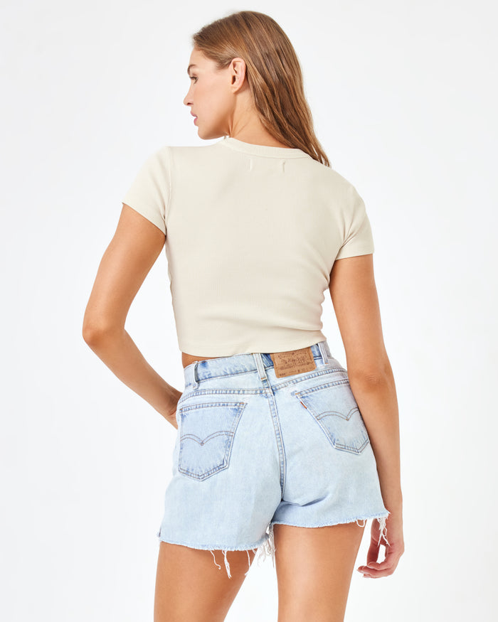 Back view of a model wearing the LSPACE aligrace Michelle Denim Short in blue, styled with a cream ribbed crop tee.