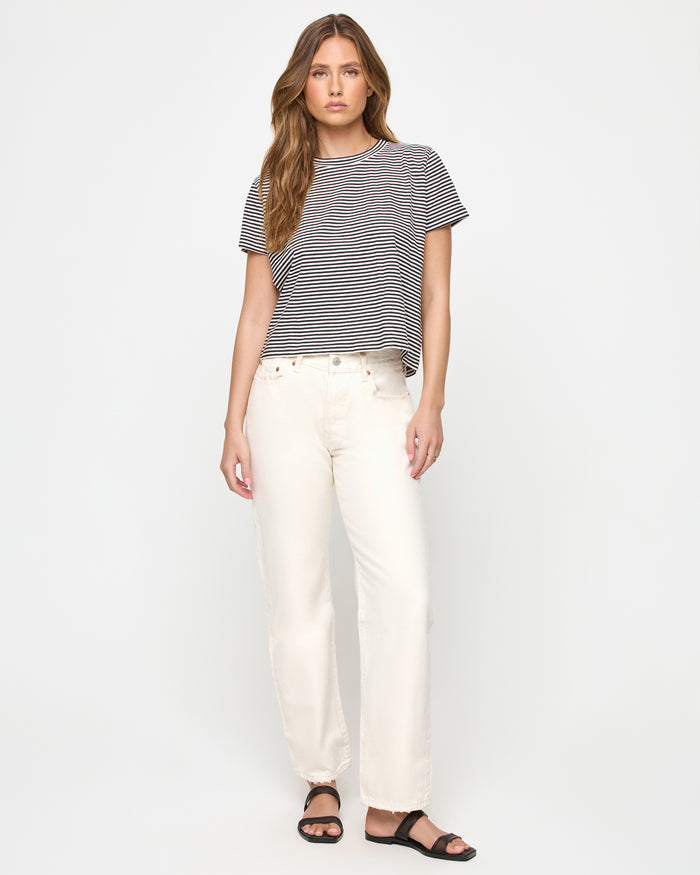 Full-length front view of a model wearing the LSPACE All Day Top in black-cream, a relaxed cropped boxy striped t-shirt with a crew neckline and short sleeves, styled with wide-leg jeans.