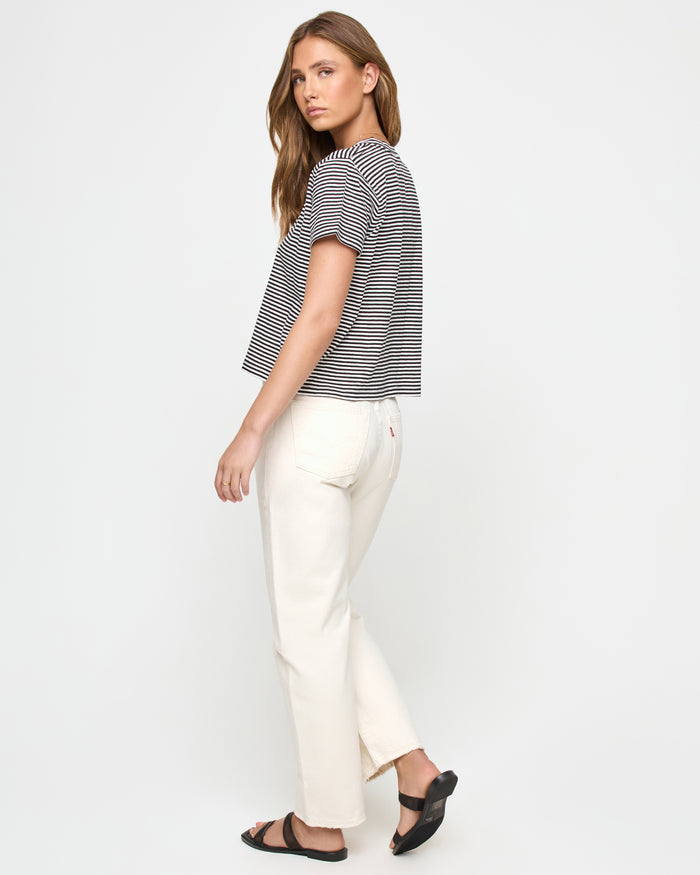 Side view of a model wearing the LSPACE All Day Top in black-cream, highlighting the relaxed cropped boxy fit and horizontal stripe pattern.