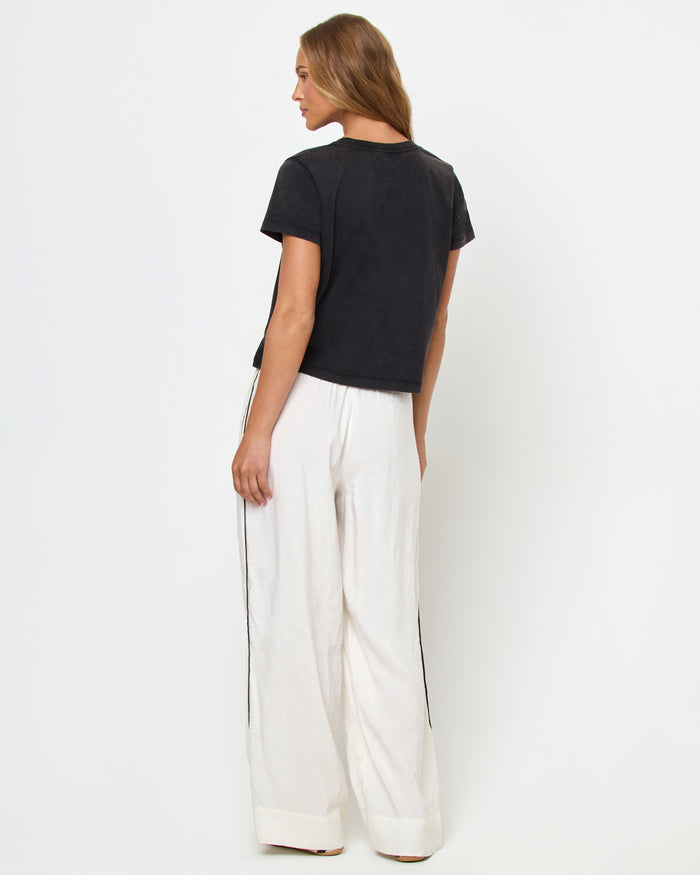 Back view of a model wearing the LSPACE All Day Top in black, styled with white wide-leg track pants.