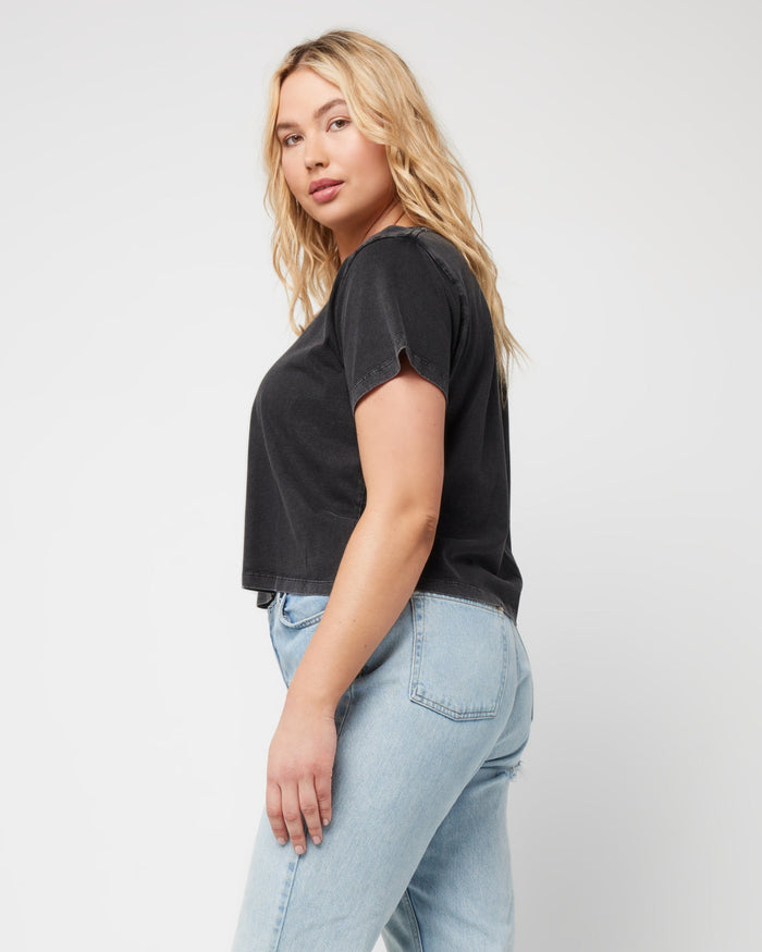 Side view of a model wearing the LSPACE All Day Top in black, styled with light wash jeans.