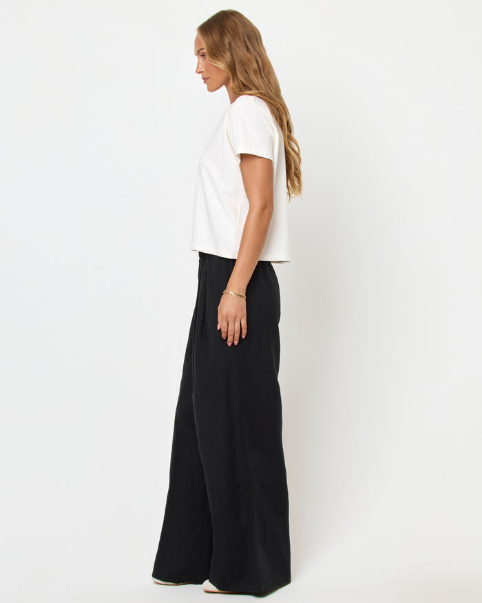 Side view of a model wearing the LSPACE All Day Top in cream, styled with black wide-leg pants.