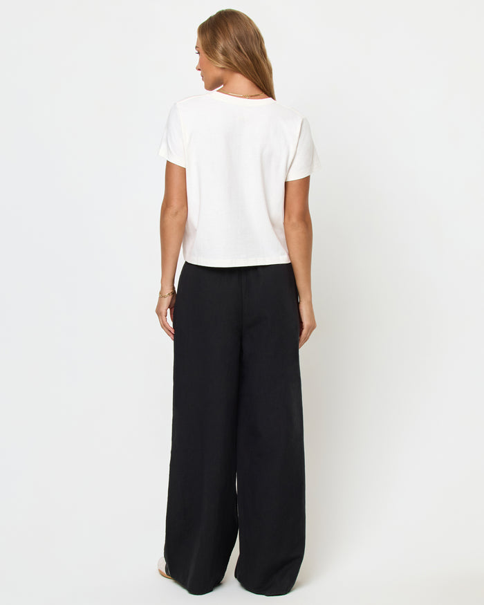 Back view of a model wearing the LSPACE All Day Top in cream, styled with black wide-leg pants.