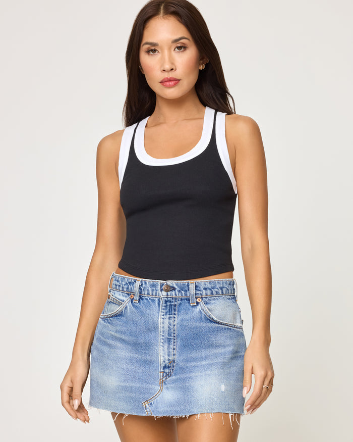 Close-up front view of a model wearing the LSPACE Ash Tank in black white, highlighting the black ribbed body with white contrast trim at the neckline and straps.