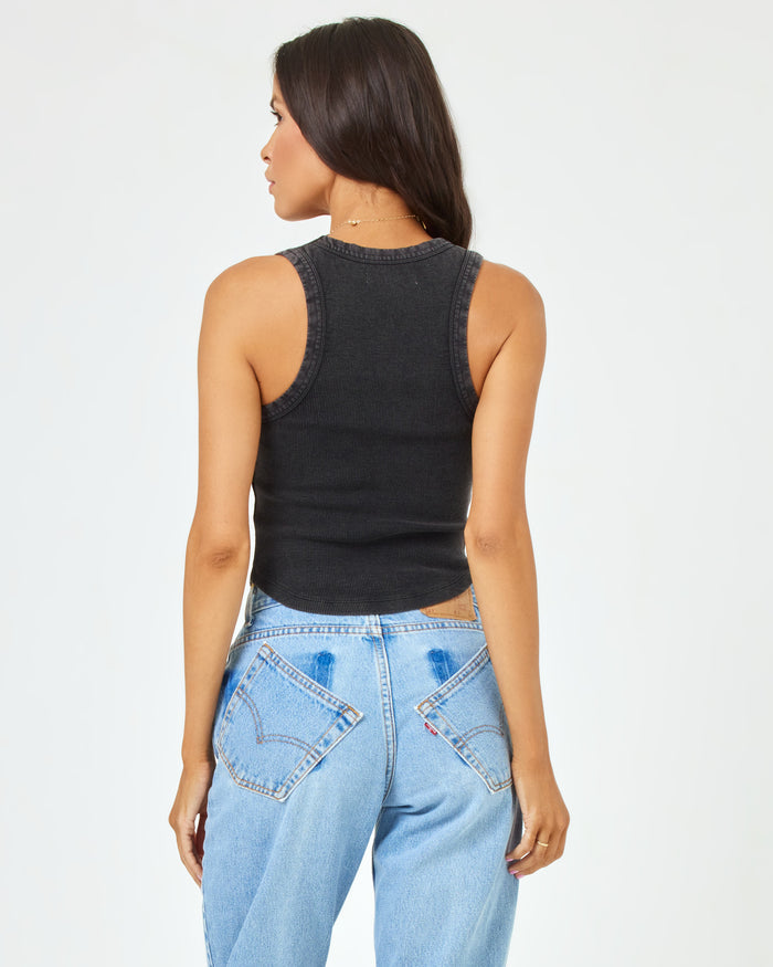 Back view of a model wearing the LSPACE Ash Tank in black, showing the racerback detail, styled with light wash jeans.