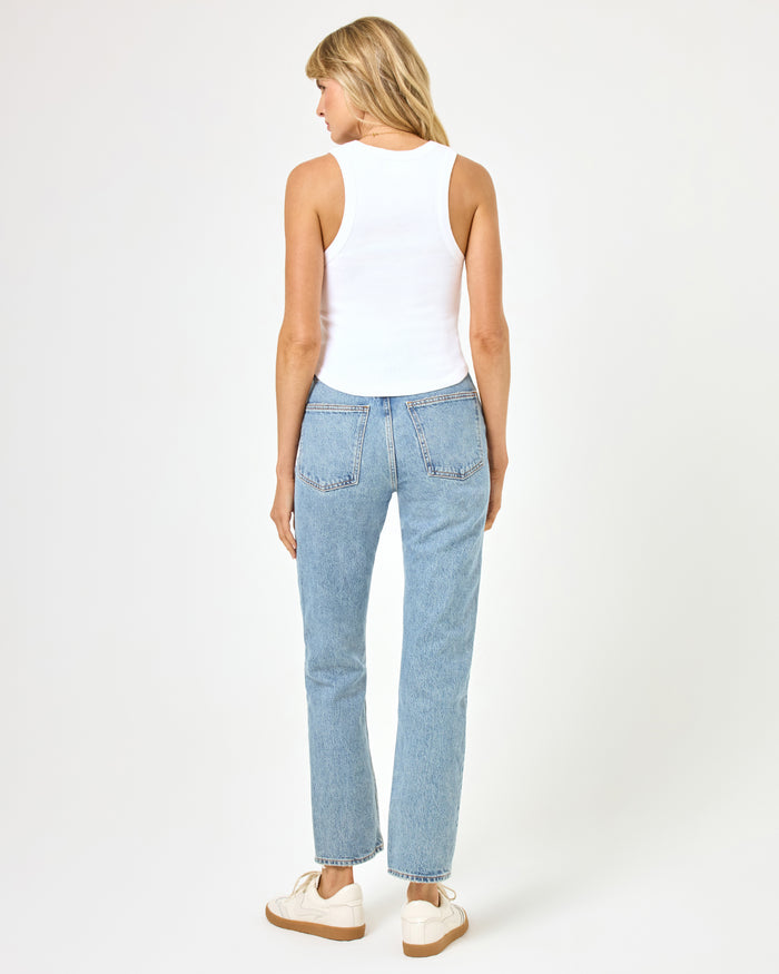 Back view of a model wearing the LSPACE Ash Tank in white, a ribbed crop tank, styled with jeans.