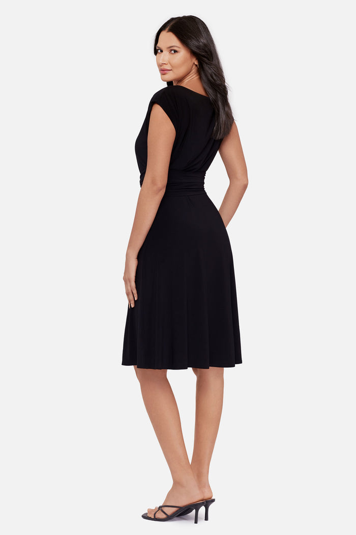 Woman faced left wearing a black short sleeve mid length dress