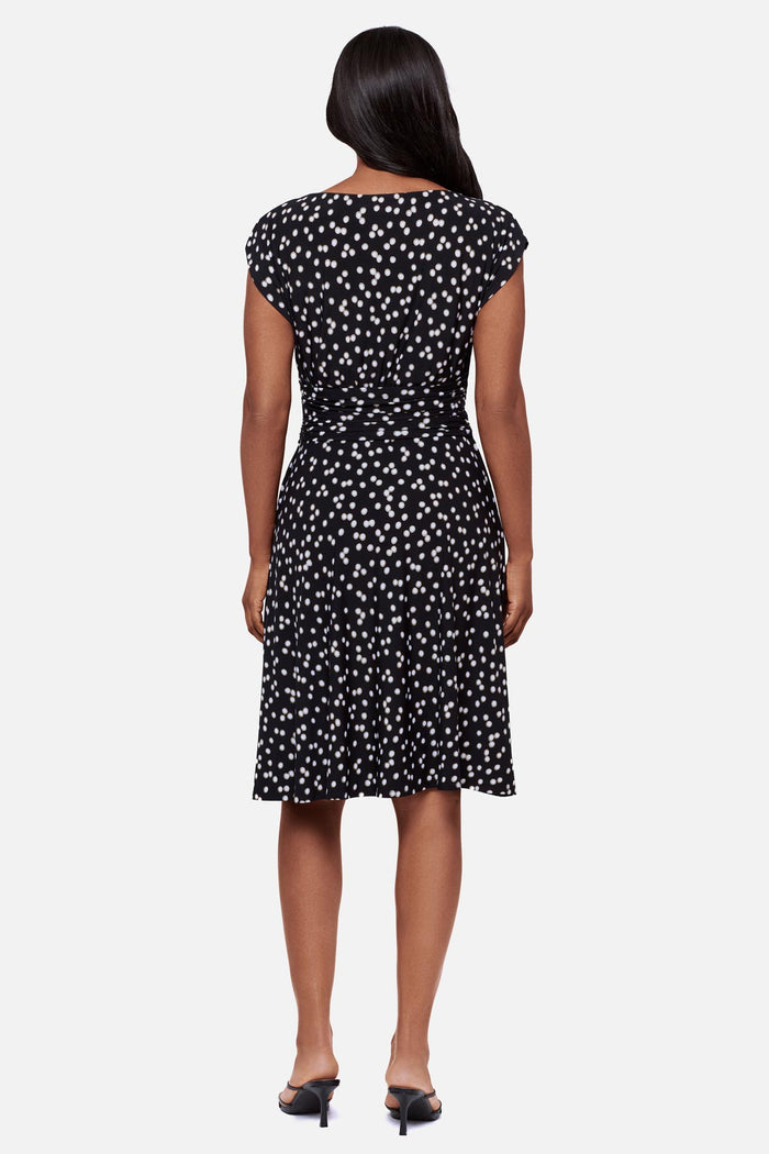 Woman faced away wearing a black and white polka dot short sleeve mid length dress