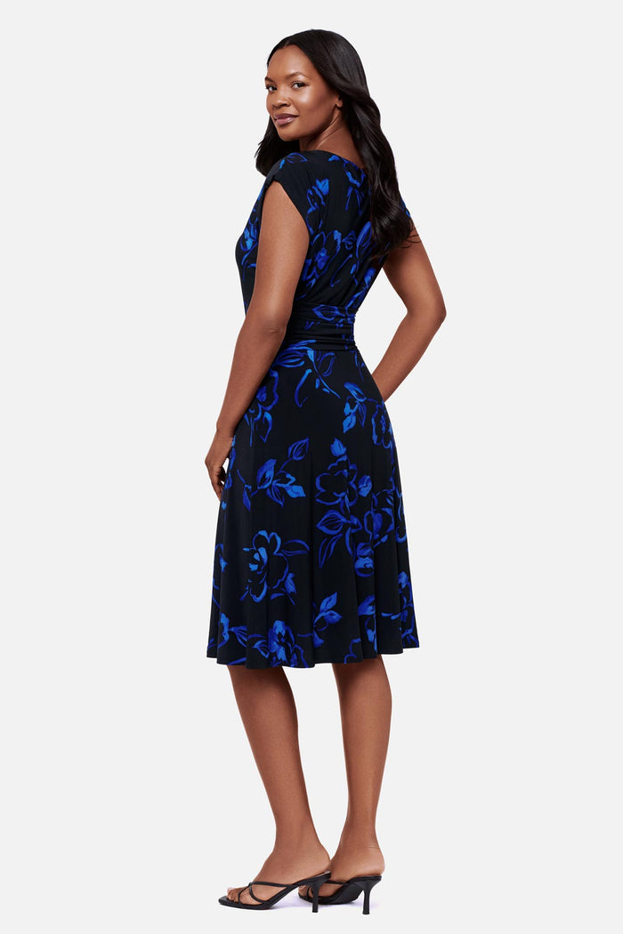 Woman turned left wearing a black and blue floral printed short sleeve mid length dress