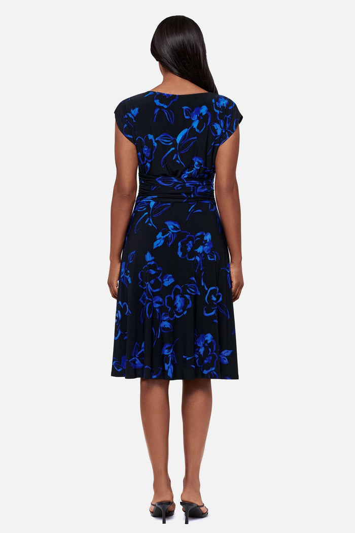 Woman turned away wearing a black and blue floral printed short sleeve mid length dress