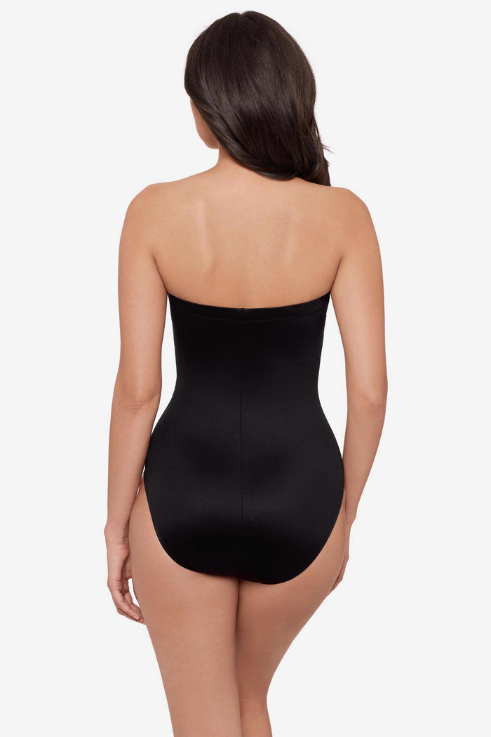 Woman turned away wearing a strapless green and white feather printed one-piece swimsuit