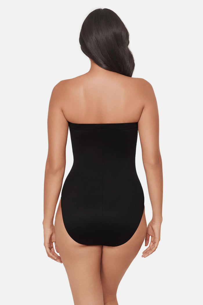 Woman turned away wearing a multicolored abstract floral printed bandeau one-piece swimsuit