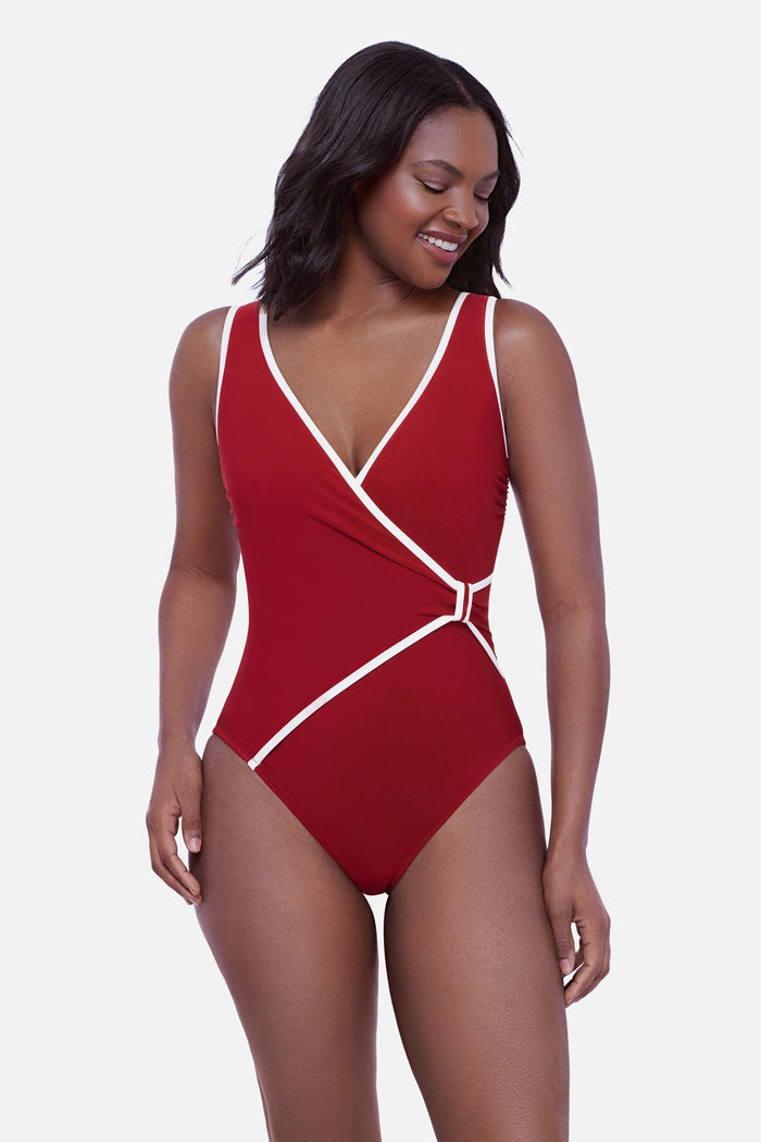 Woman wearing a cherry red one-piece swimsuit with white piping on the edges