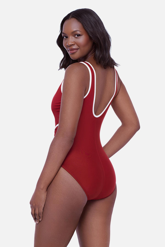 Woman turned left wearing a cherry red one-piece swimsuit with white piping on the edges