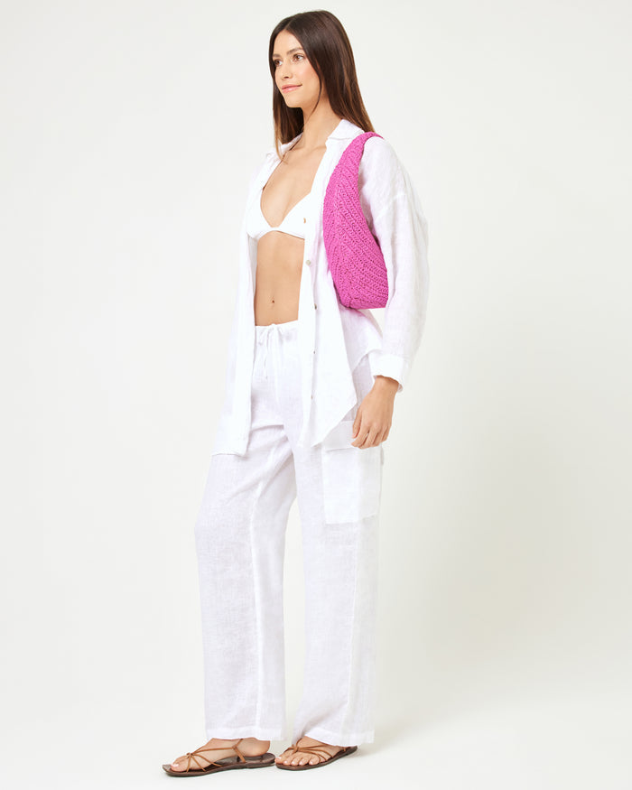 Model wearing the Aya Bag in bubblegum pink over the shoulder, paired with a white linen shirt and white wide-leg pants.