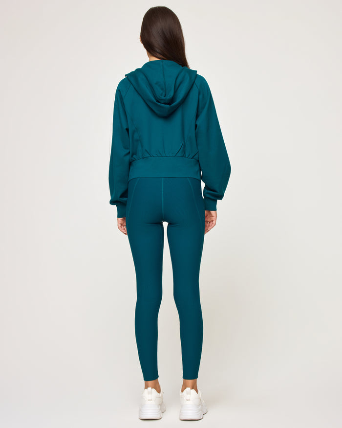 Back view of model wearing the Back To Back Jacket in deep teal-cream showing the cream contrast back panel, with matching deep teal-cream Back To Back Pant.