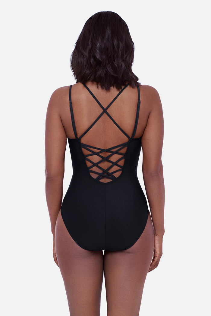 Woman faced away wearing a black one-piece swimsuit with double straps and a lattice back