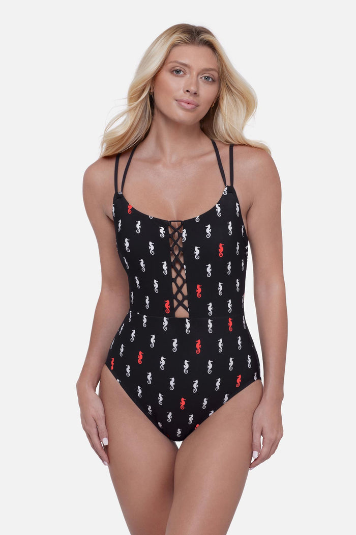 Woman wearing a black one-piece swimsuit with a red and white seahorse print