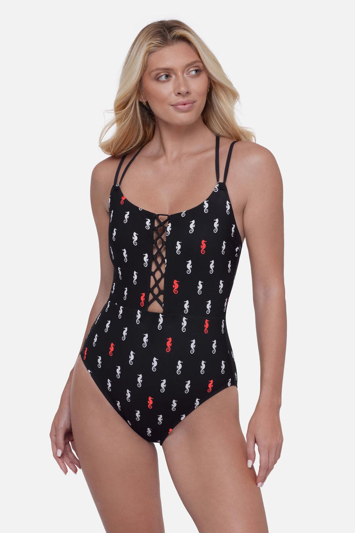 Woman wearing a black one-piece swimsuit with a red and white seahorse print
