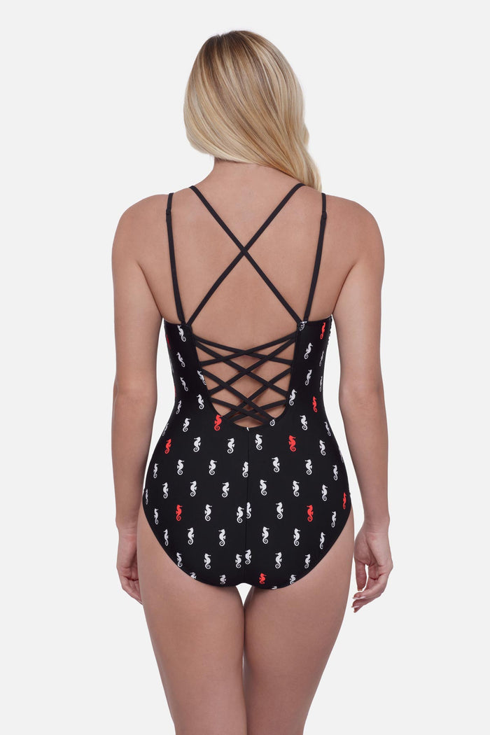 Woman turned away wearing a black one-piece swimsuit with a red and white seahorse print