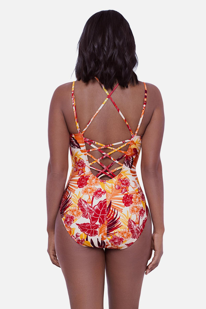 Woman faced away wearing a multicolored palm leaf printed one-piece swimsuit with lattice back