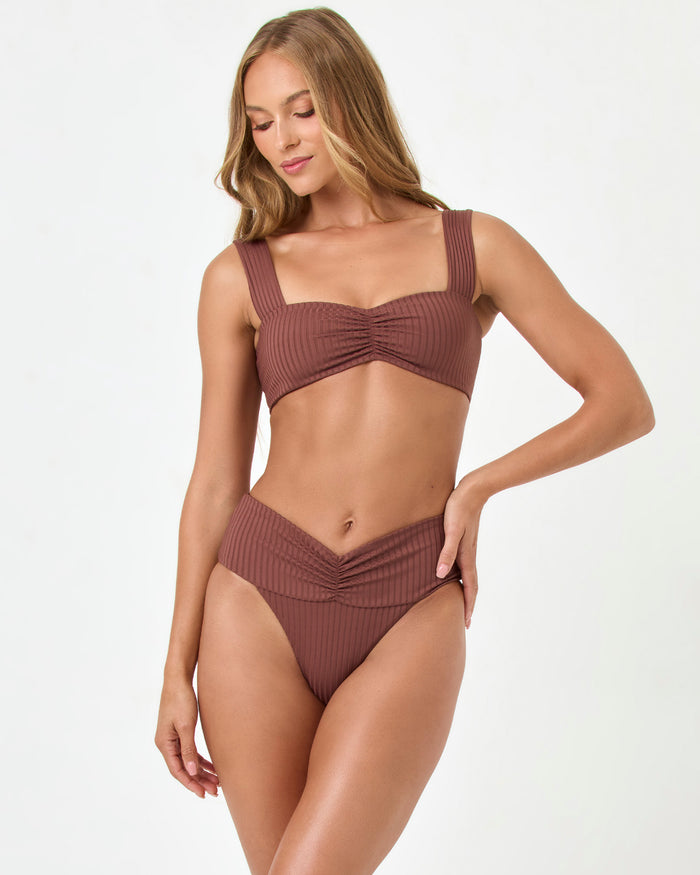 Front view of a model wearing the LSPACE cafe Bardot Bikini Bottom with a V-shaped ruched waistband and a matching ribbed Marlee Bikini Top.