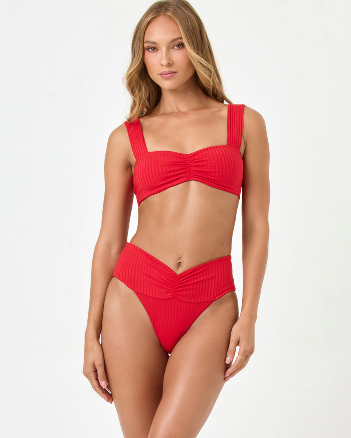 Front view of a model wearing the LSPACE flame Bardot Bikini Bottom with a V-shaped ruched waistband and a matching ribbed Marlee Bikini Top.