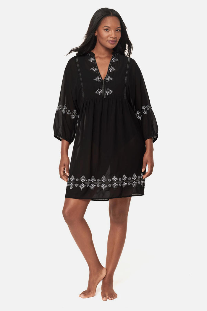 Woman wearing a black beach dress swim cover up with geometric details along the edges