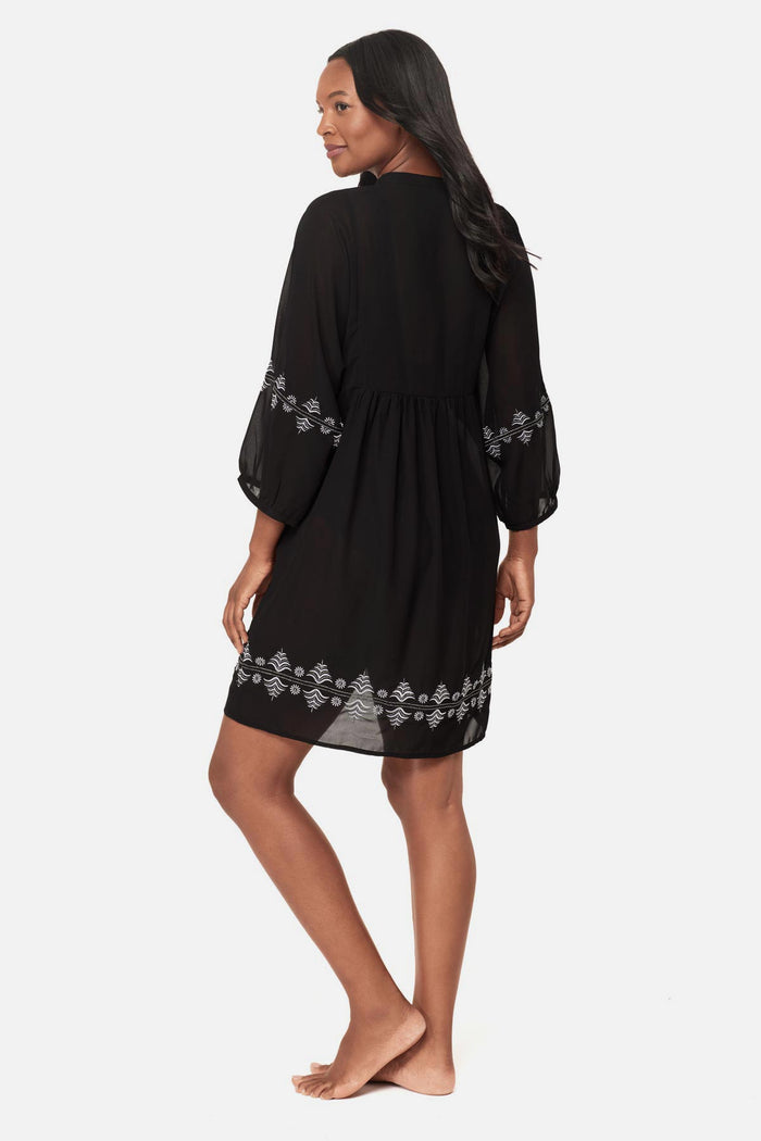 Woman turned left wearing a black beach dress swim cover up with geometric details along the edges