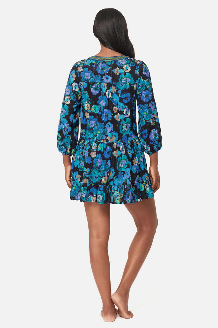 Woman turned away wearing a black and blue floral printed swim cover up dress
