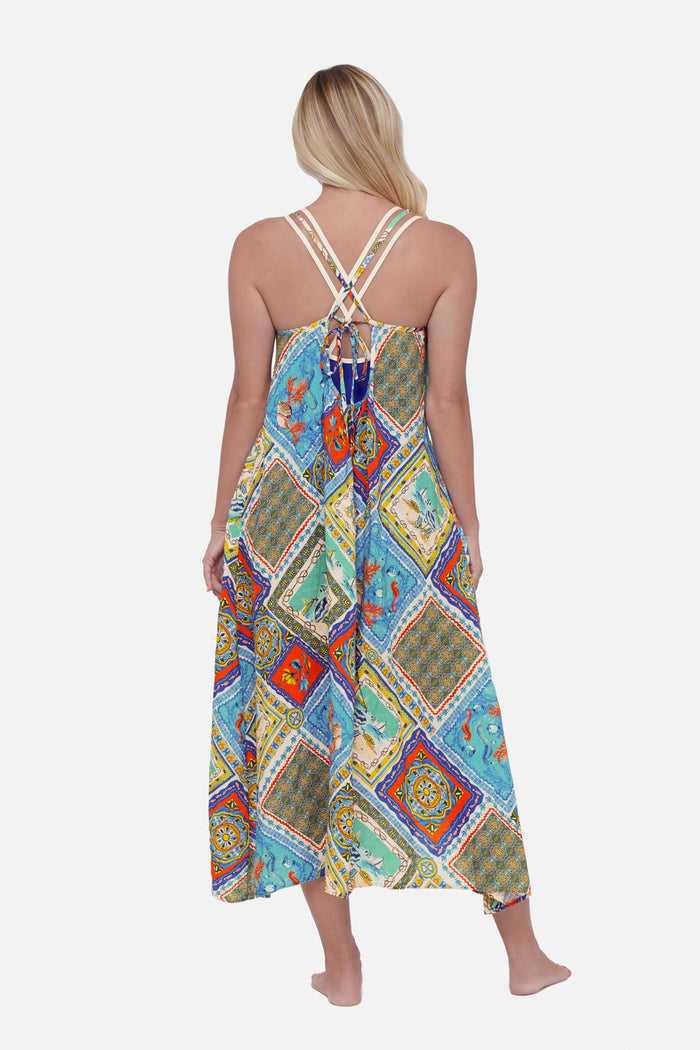 Woman faced away wearing a printed swim cover up with detailed artwork in each tile
