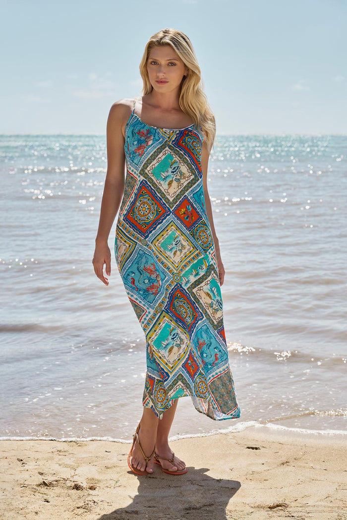 Woman on beach wearing a printed swim cover up with detailed artwork in each tile
