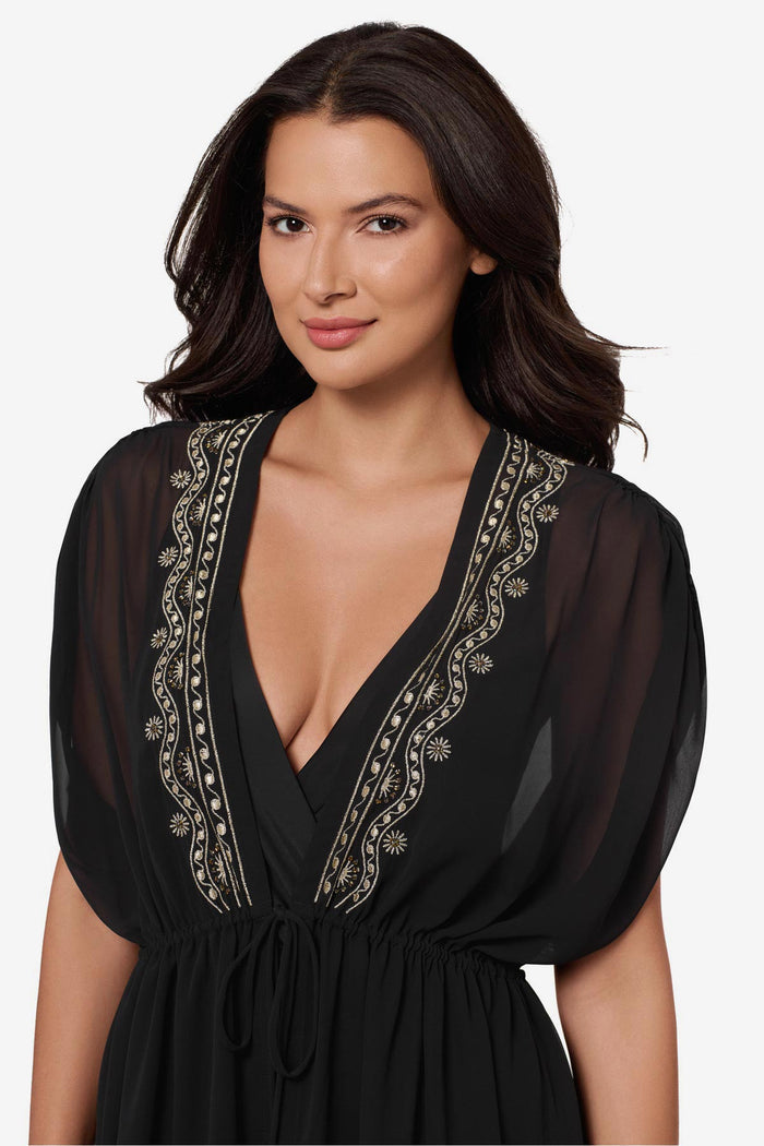 Close up of woman wearing a black kimono swim cover up with embellishments along the opening
