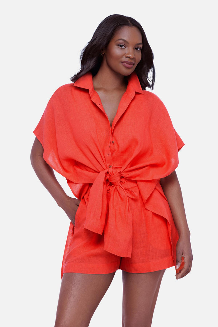 Woman wearing an orange oversized swim cover up shirt tied in the front