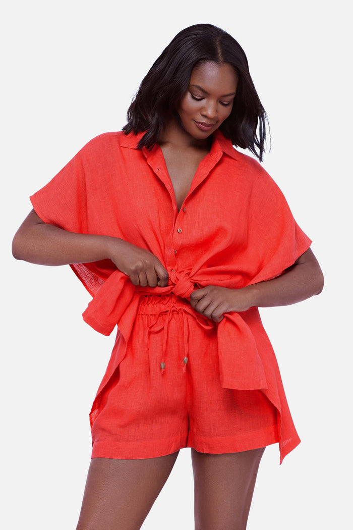 Woman wearing an orange oversized swim cover up shirt tied in the front