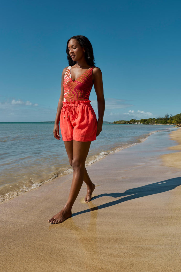 Woman on beach wearing an orange swim short cover up